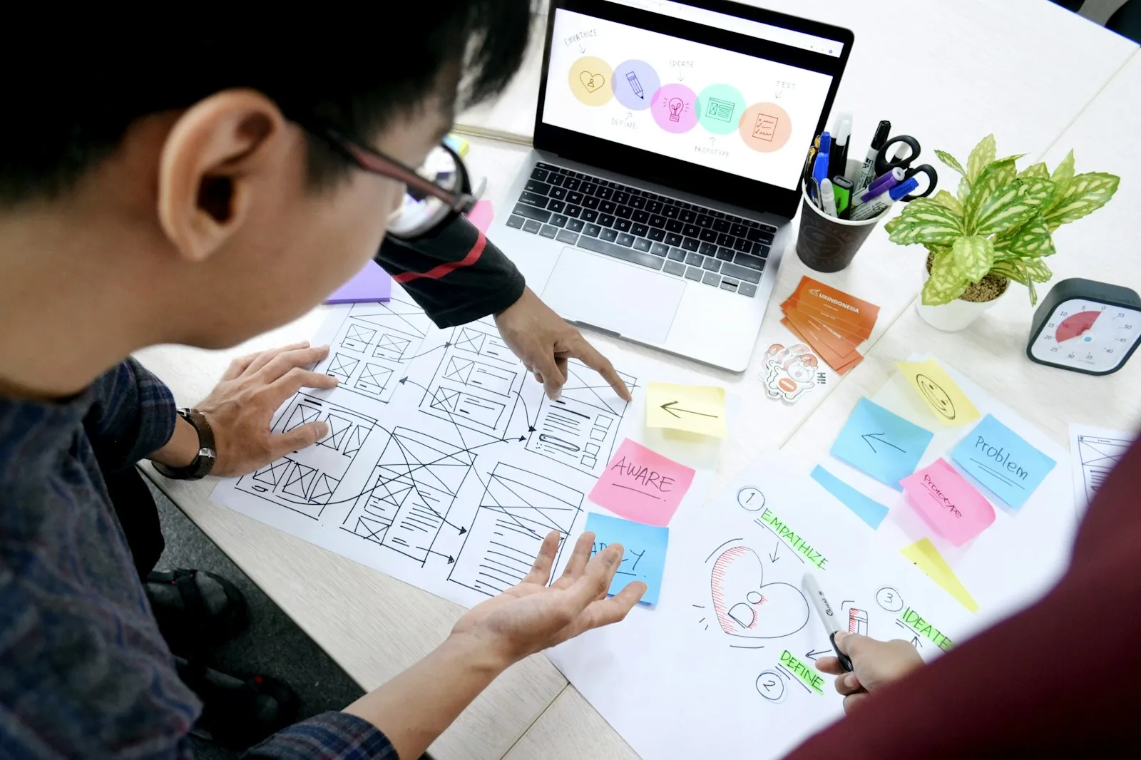 UX designers comparing website wireframes and platform requirements at a desk