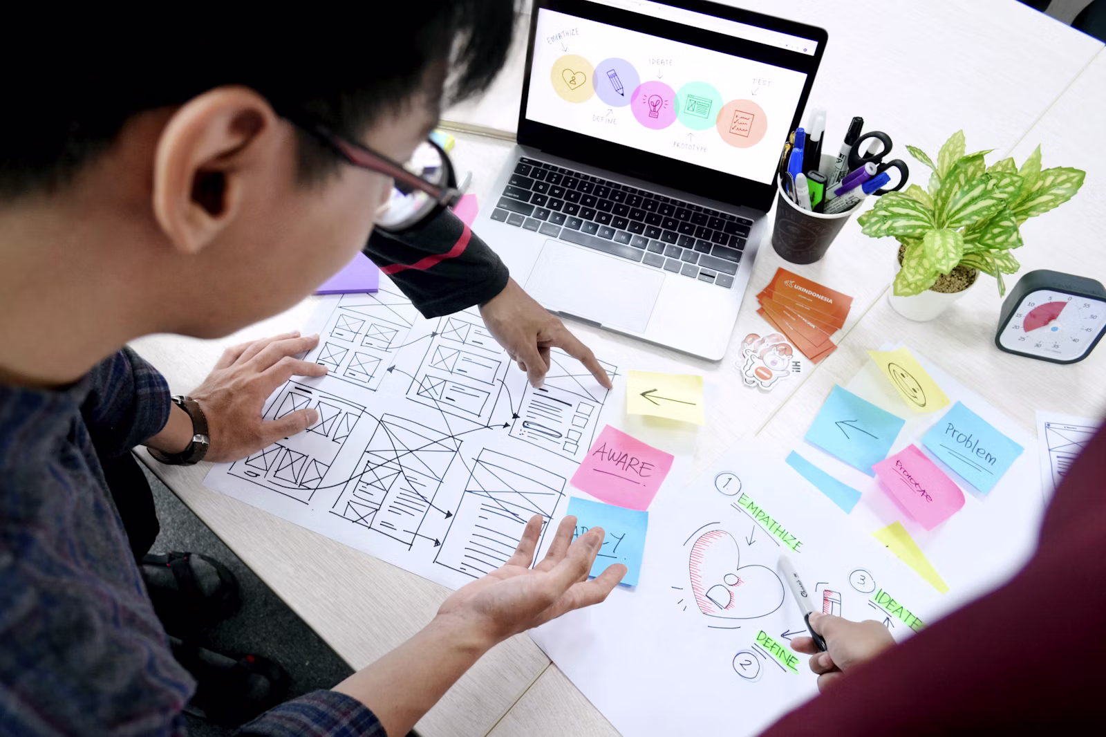 UX designers comparing website wireframes and platform requirements at a desk