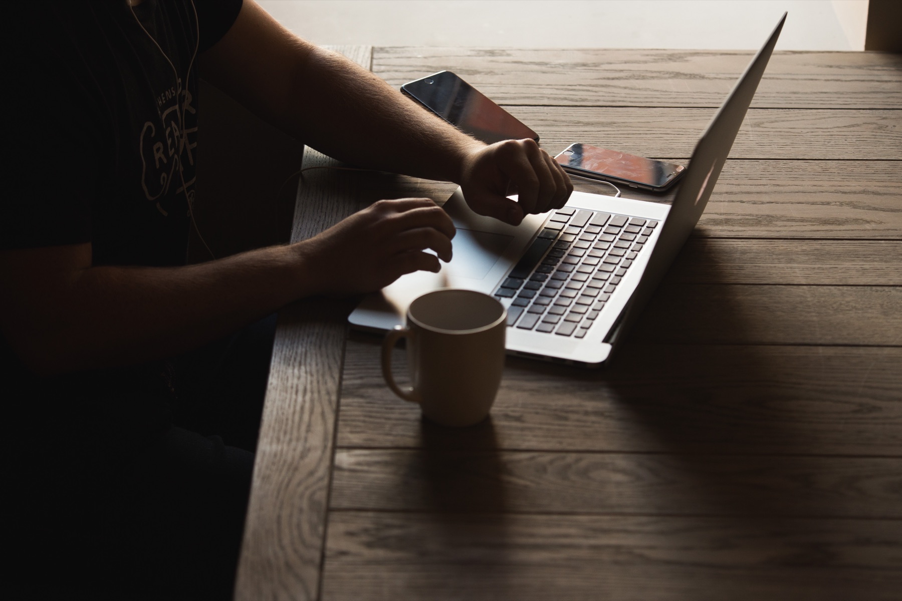 Mobile app developer working at a laptop while reviewing a smartphone
