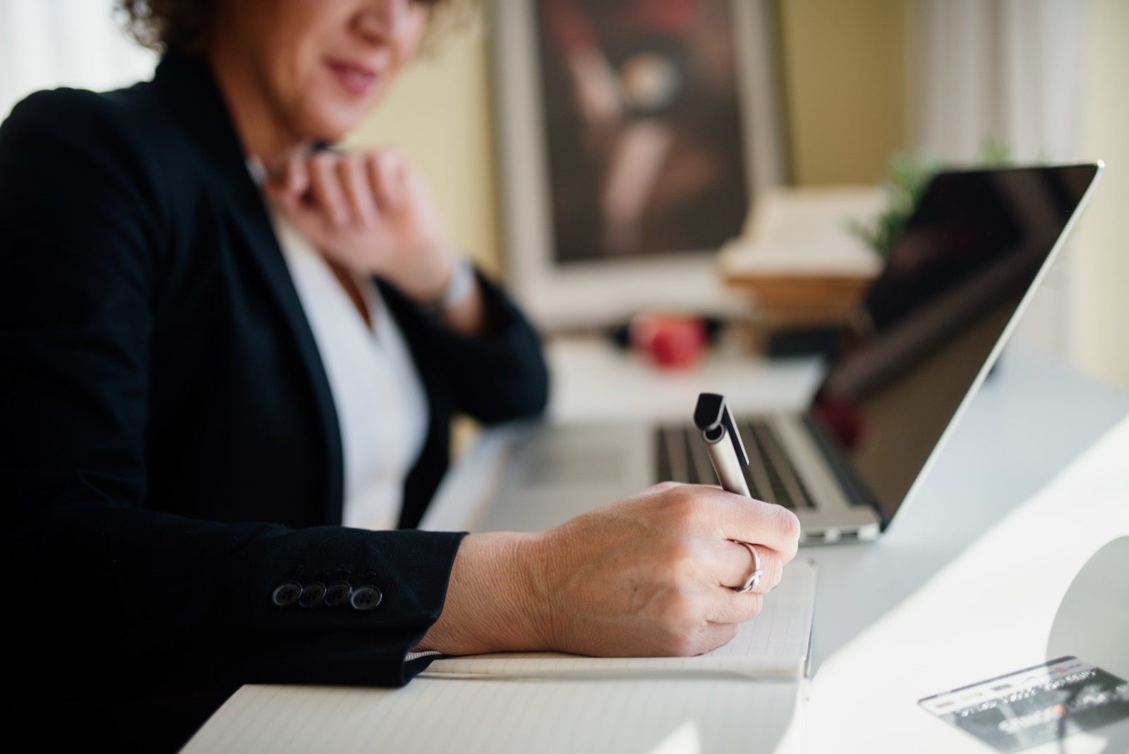 Business professional taking notes beside a laptop while planning a website project