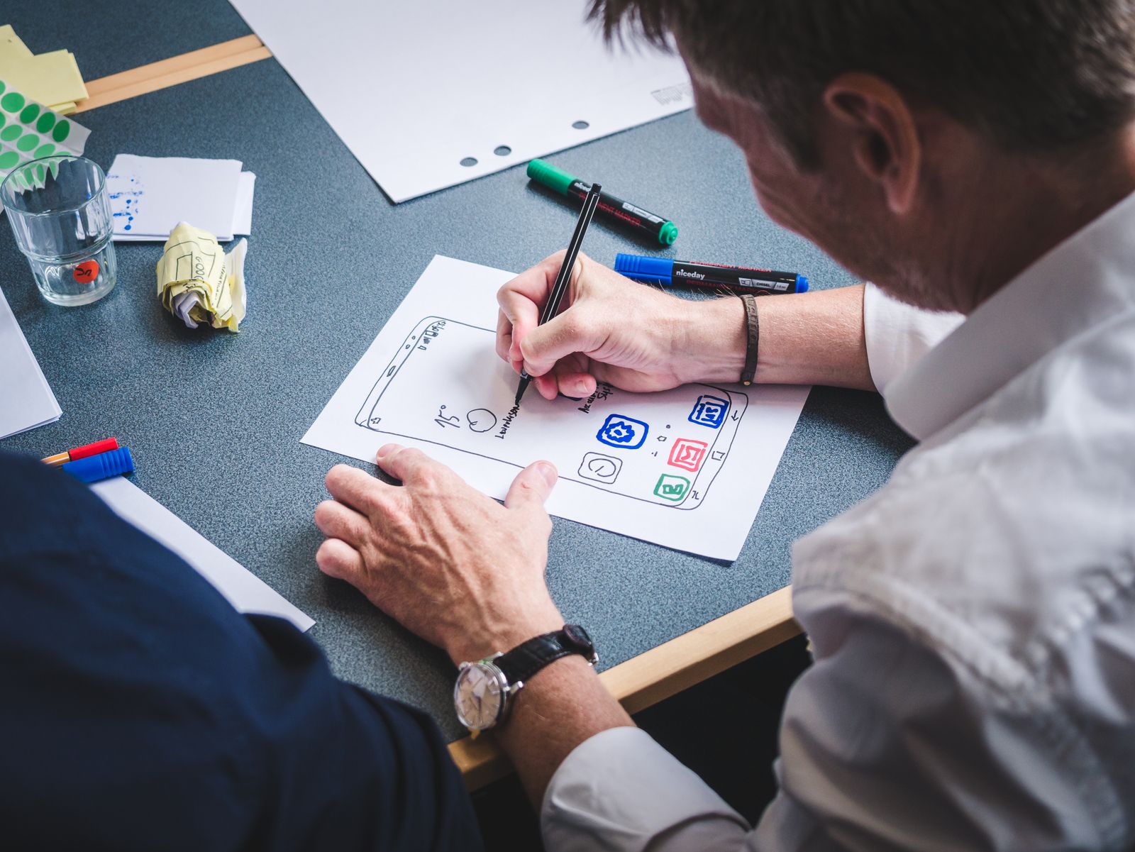 Designer sketching a mobile app interface on paper during a business app redesign