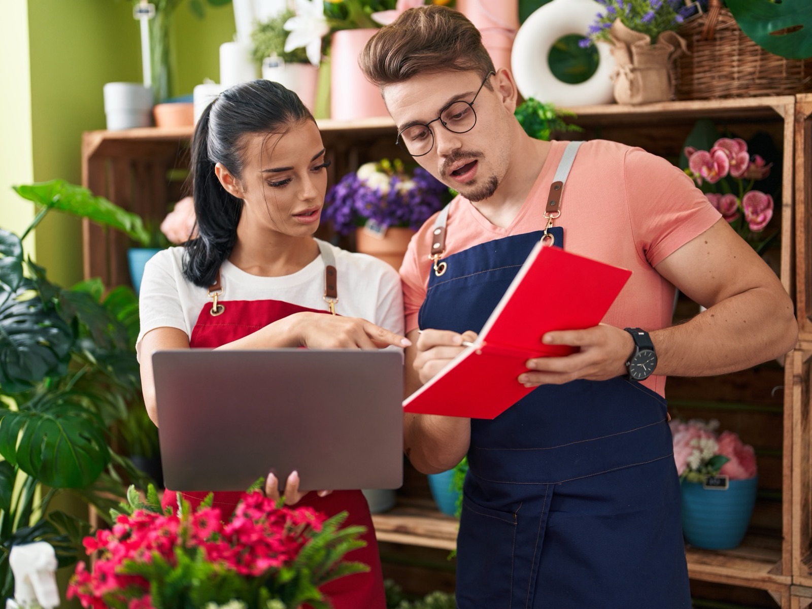 Two small business owners reviewing their website together on a laptop in their flower shop