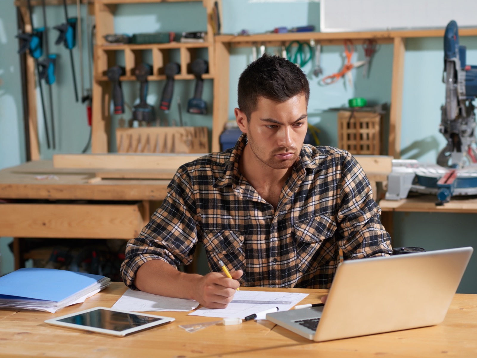 Contractor in his workshop checking his business website on a laptop